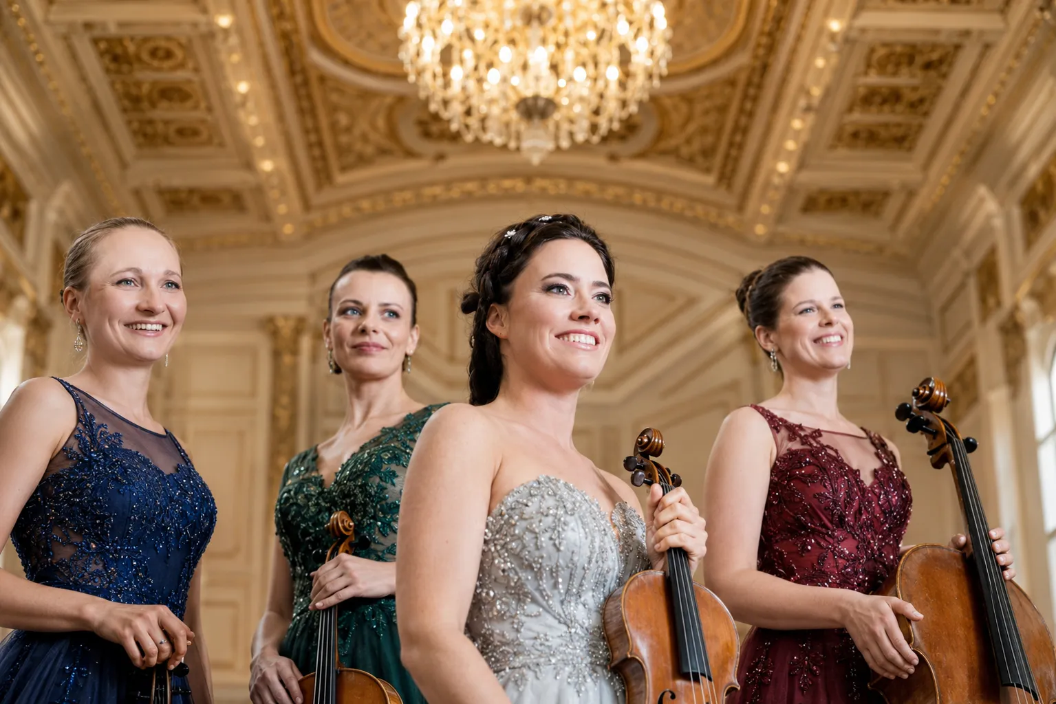 Das Streichquartett von Maja Music lächelt elegant mit ihren Streichinstrumenten in einem prunkvollen, goldenen Konzertsaal.